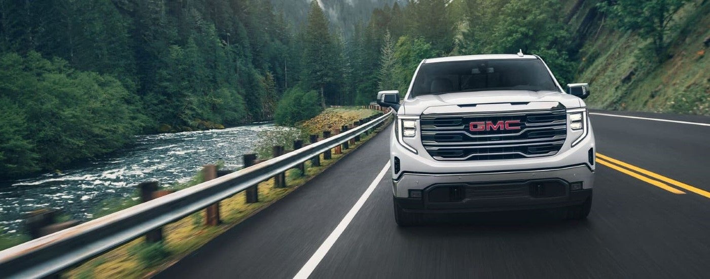 Front view of a white 2024 GMC Sierra 1500 SLE driving.